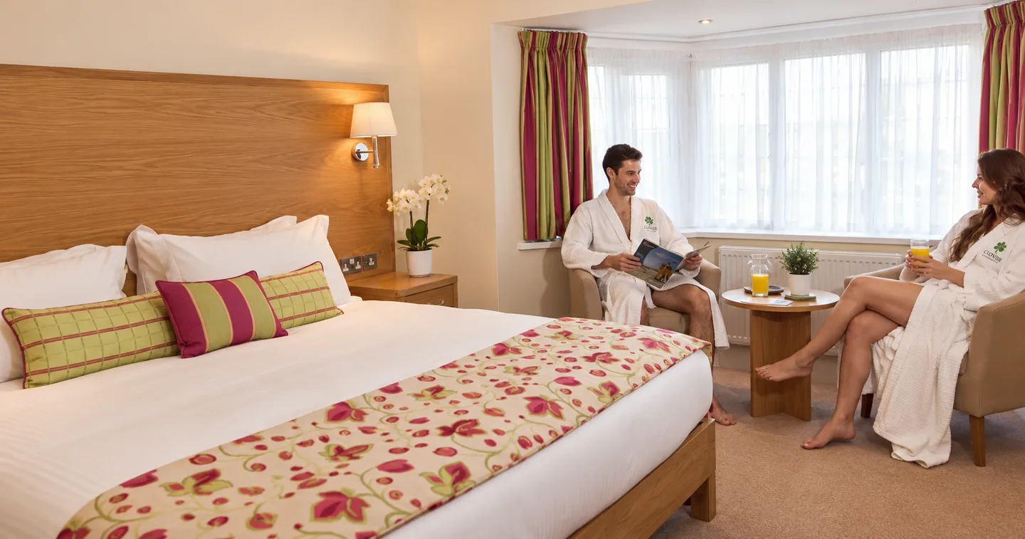 A couple relaxing in robes in an en-suite bedroom on a couples spa break in Birmingham