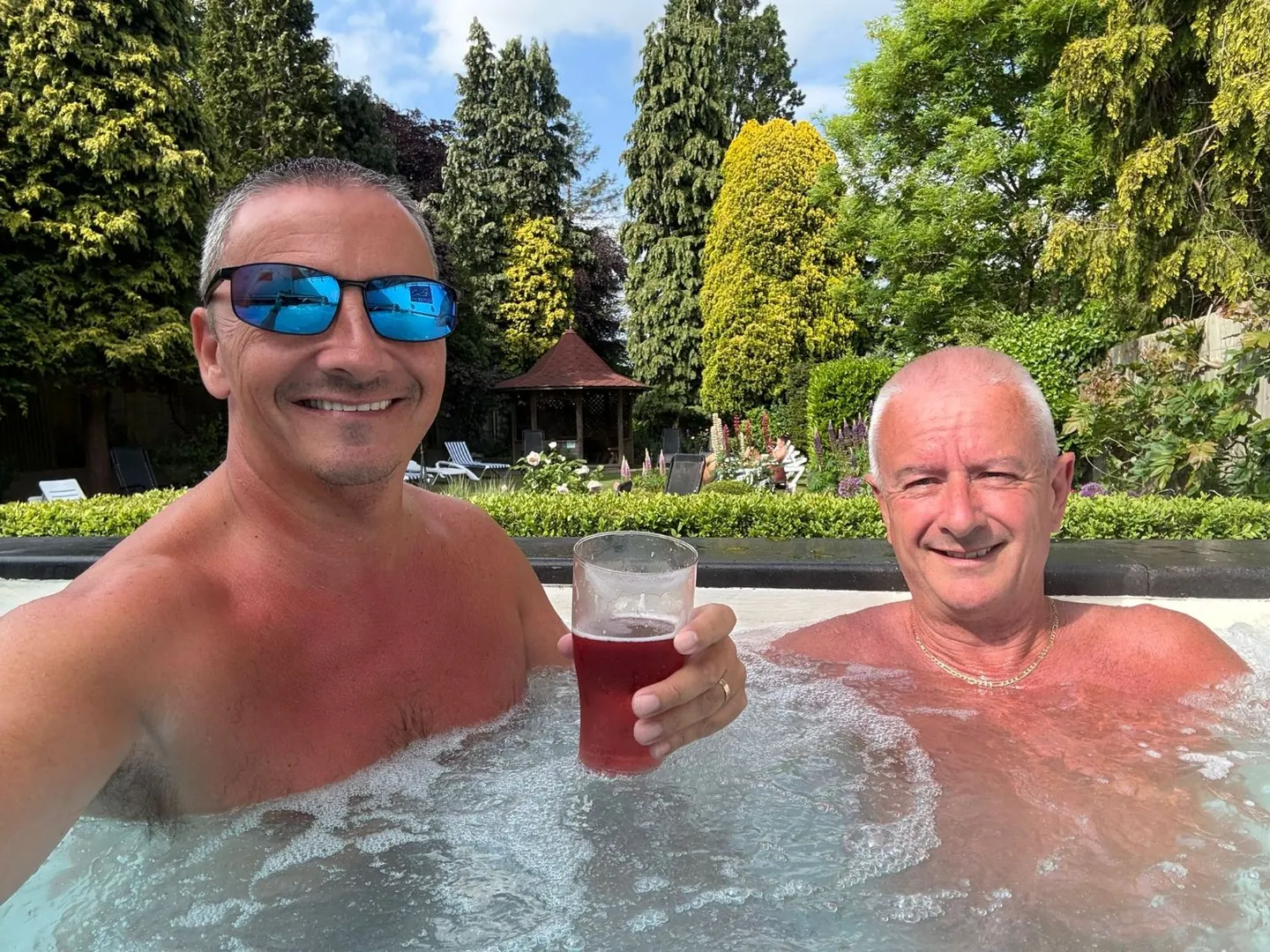 A couple smiling in the garden hot tub on a couples spa day in Birmingham
