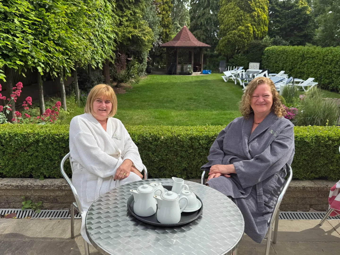 A couple in robes having tea in the garden at the end of a couples spa day